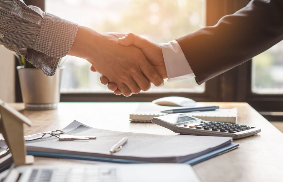 Two people shaking hands over a contract